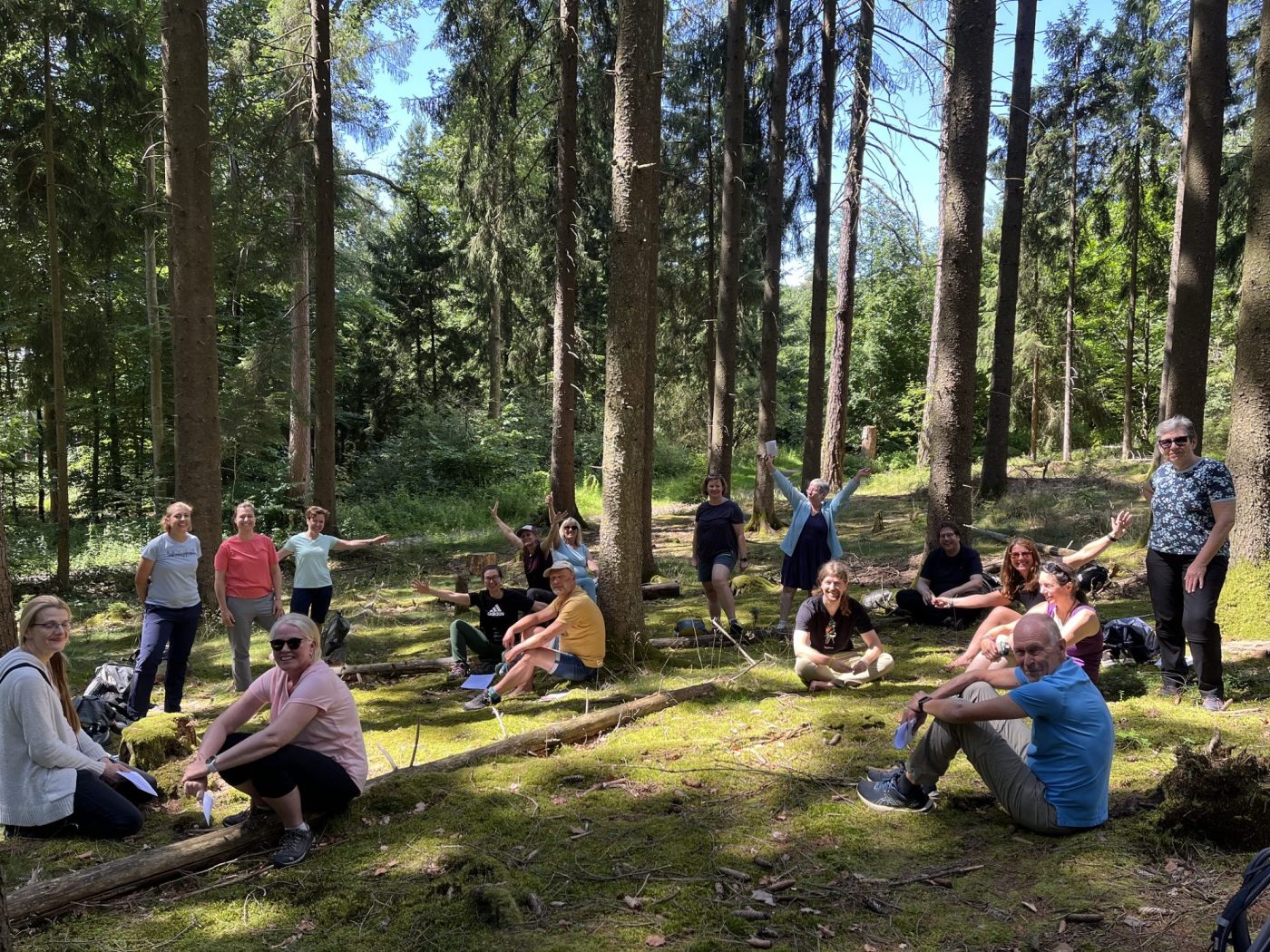 Fröhliche Seminargruppe sitzt auf einer Waldlichtung
