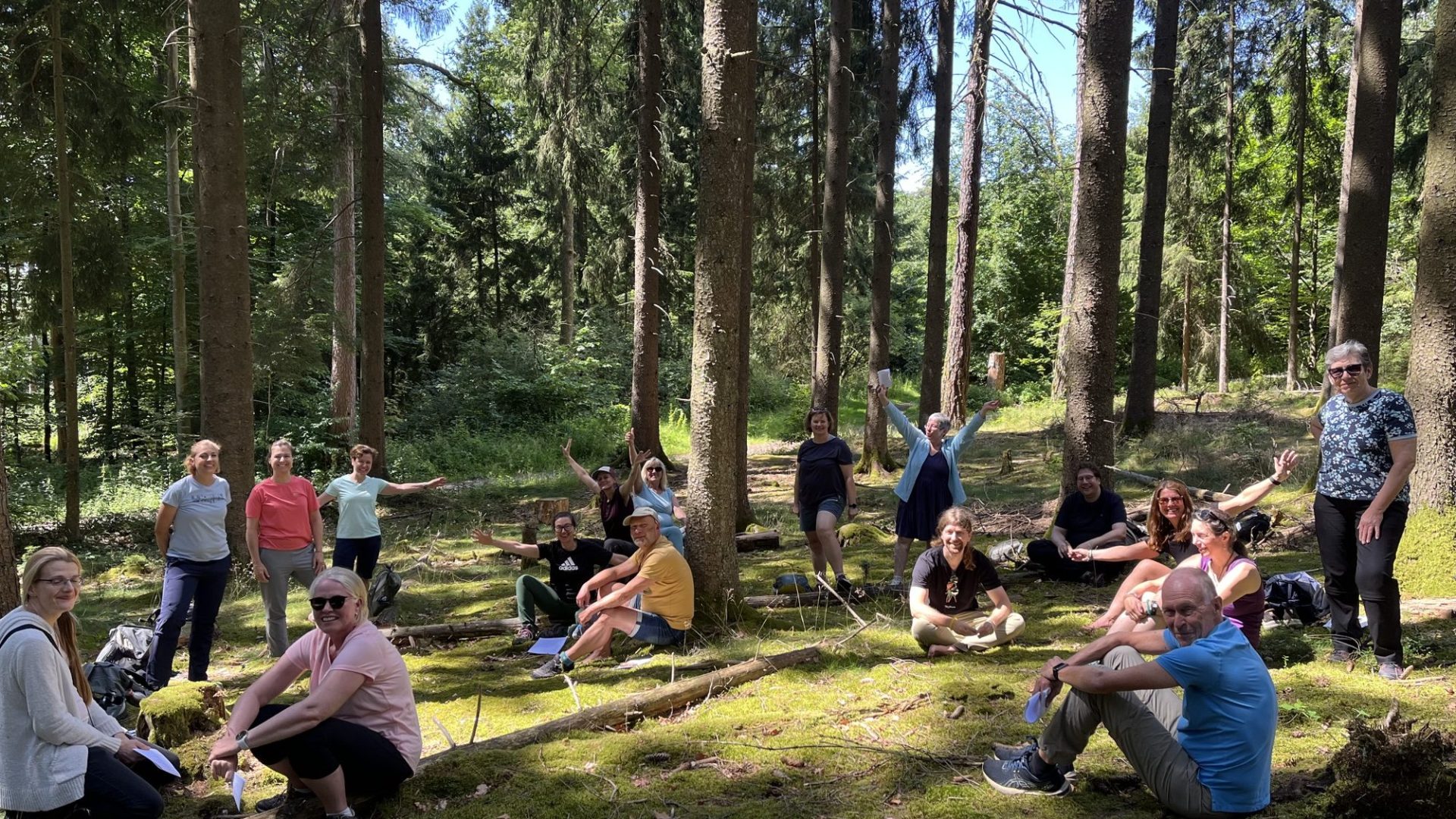Fröhliche Seminargruppe sitzt auf einer Waldlichtung