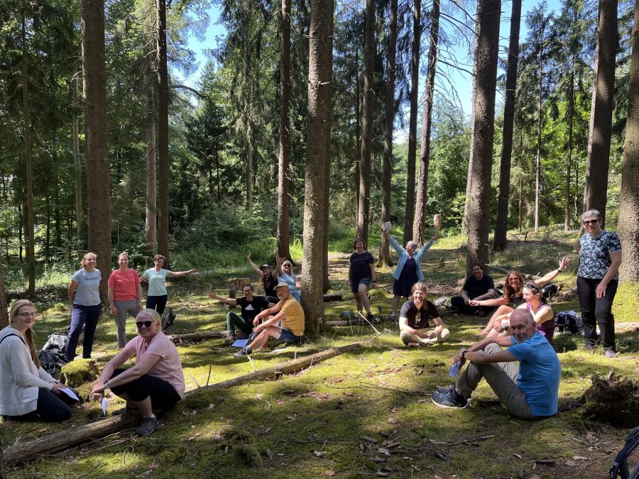 Fröhliche Seminargruppe sitzt auf einer Waldlichtung
